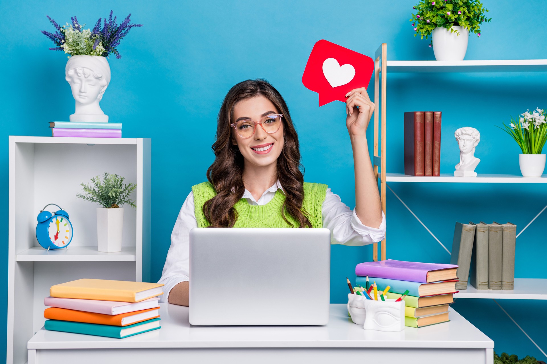 Photo portrait of attractive young woman heart notification icon workspace dressed stylish green clothes isolated on blue color background at Sprout DG Social Media Marketing Agency